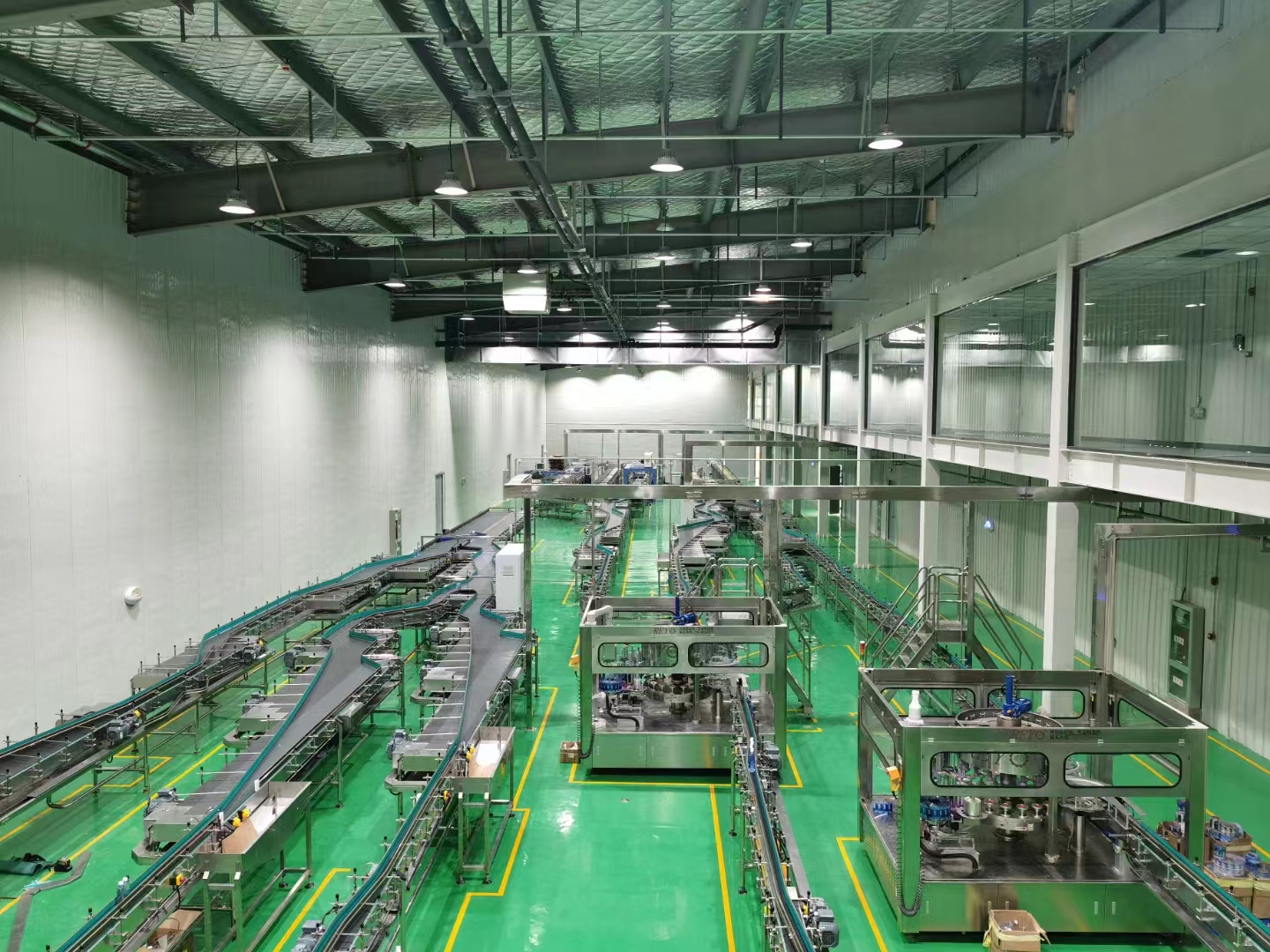 Real bottled water production line with conveyors and filling blocks in a clean industrial hall